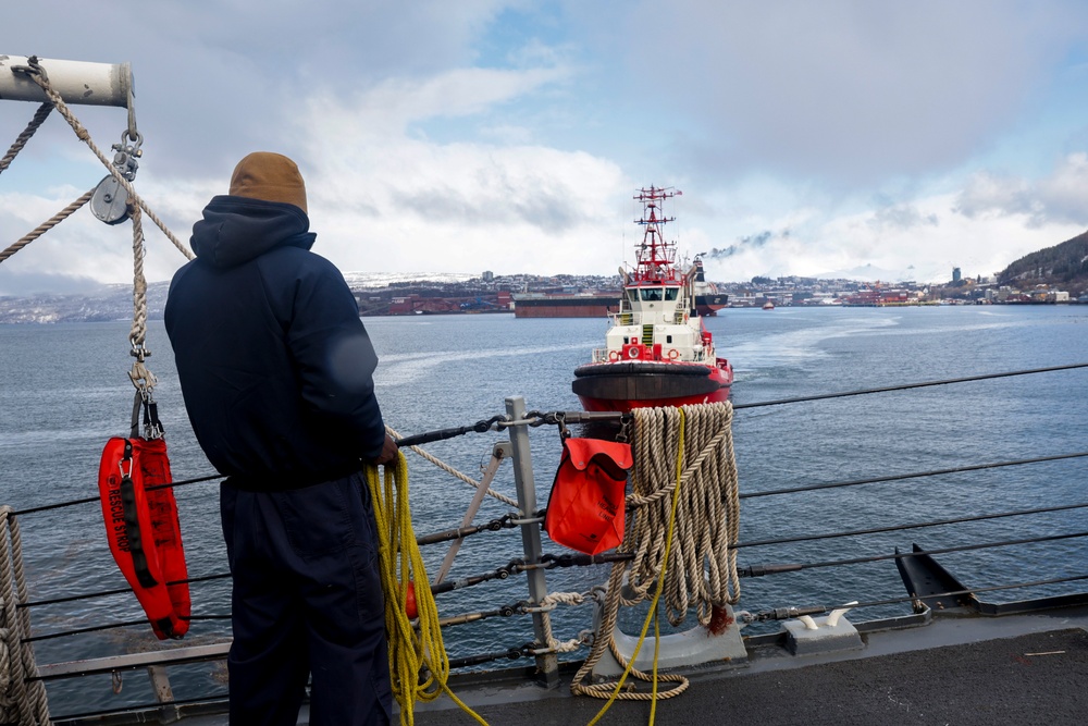U.S. Navy Sailor prepares to throw a heaving line to an approaching tug boat.