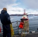 U.S. Navy Sailor prepares to throw a heaving line to an approaching tug boat.
