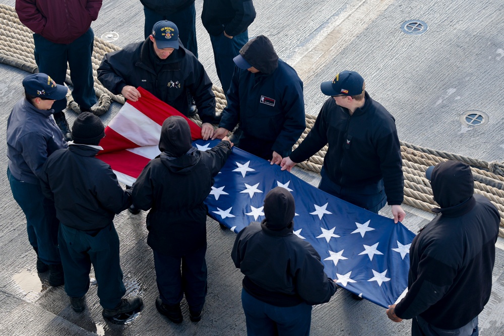 U.S. Navy Sailors fold the ensign during a sea-and-anchor detail