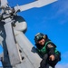 Aviation Machinist’s Mate 2nd Class Keith Gonzales receives a tail rotor blade cover to install on the tail rotor prior to stowing a MH-60R Sea Hawk helicopter
