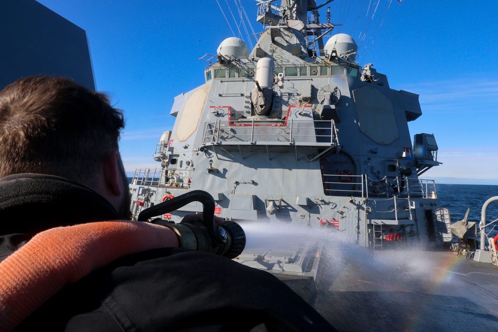 Boatswain’s Mate 1st Class Ethan Elks conducts a fresh water wash down on the fo’c’sle