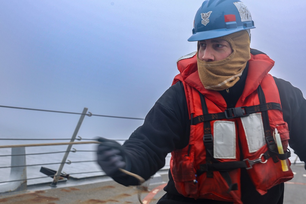 Navy Career Counselor 1st Class James McMillian heaves in a phone and distance line
