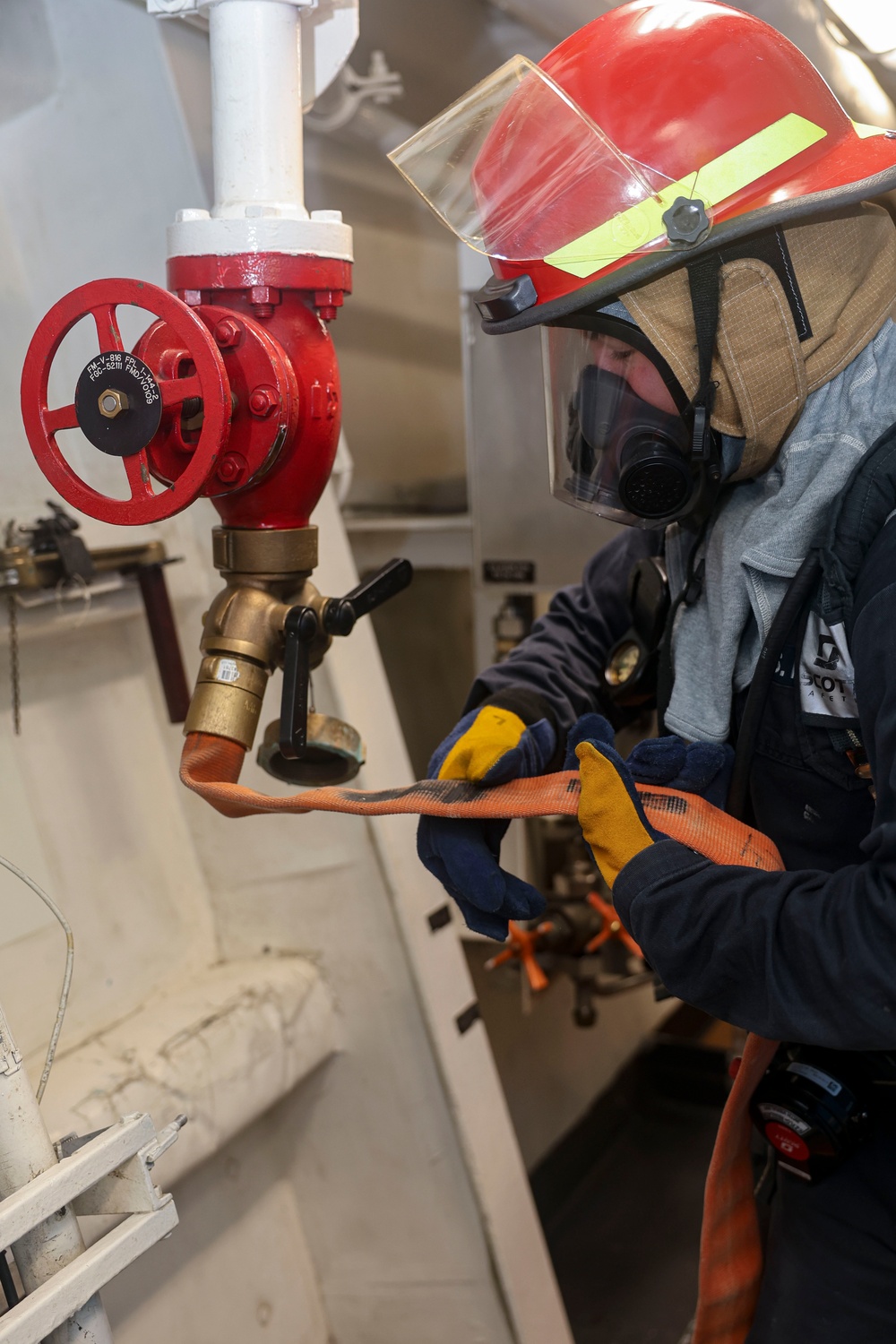 Damage Controlman 3rd Class Evan McDonald flakes out a firehose in response to a simulated fuel leak and class B fire exercise