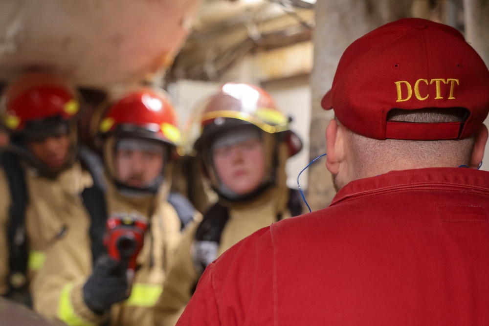 Damage Controlman 1st Class Cody Dormady provides instruction to the primary attack team