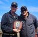 Capt. Michael Dwan, commodore, Combined Task Force (CTF) 64 receives a placard from Cmdr. Arturo Trejo