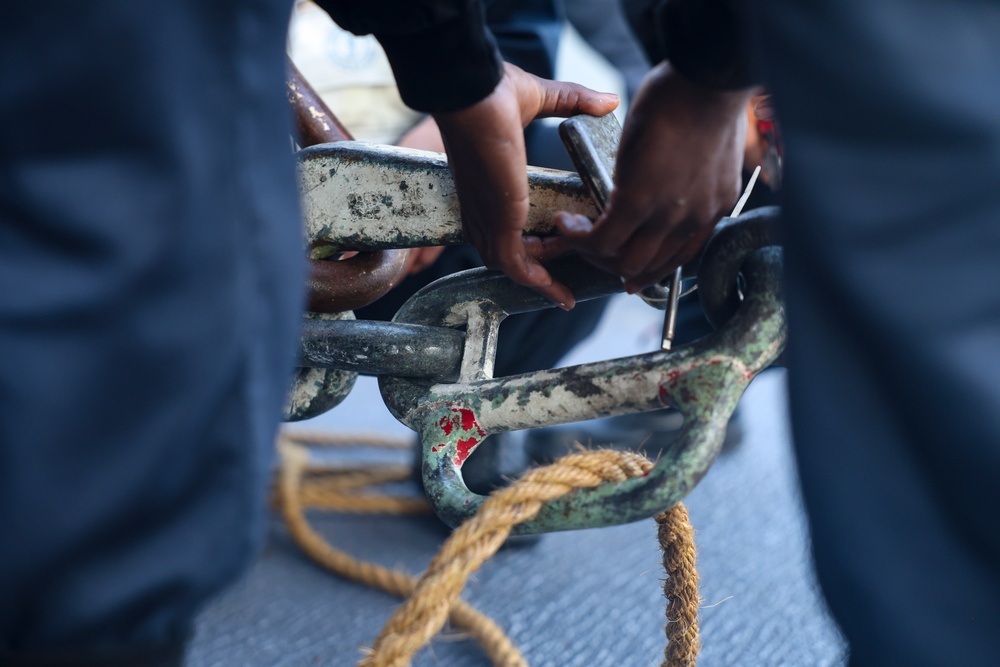 Boatswain’s Mate 3rd Class Carlens Milice connects the pelican and surf hooks on the sliding pad eye