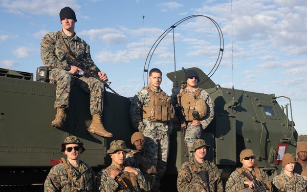 The Marines of Fox Batter 210 pose next to their High Mobility Artillery Rocket System (HIMARS) in Visby, Sweden