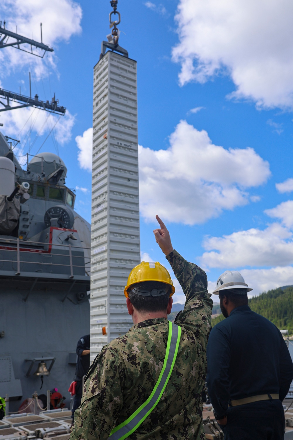 Gunner’s Mate 2nd Class Brennon Massaliga signals the crane operator to lower a Vertical Launching System