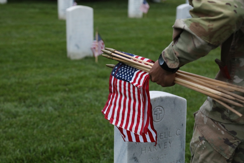 A Soldier from the 3d U.S. Infantry Regiment (The Old Guard) places American flags at headstones as part of &quot;Flags In&quot; at Arlington National Cemetery, Arlington, Va., May 22, 2025.