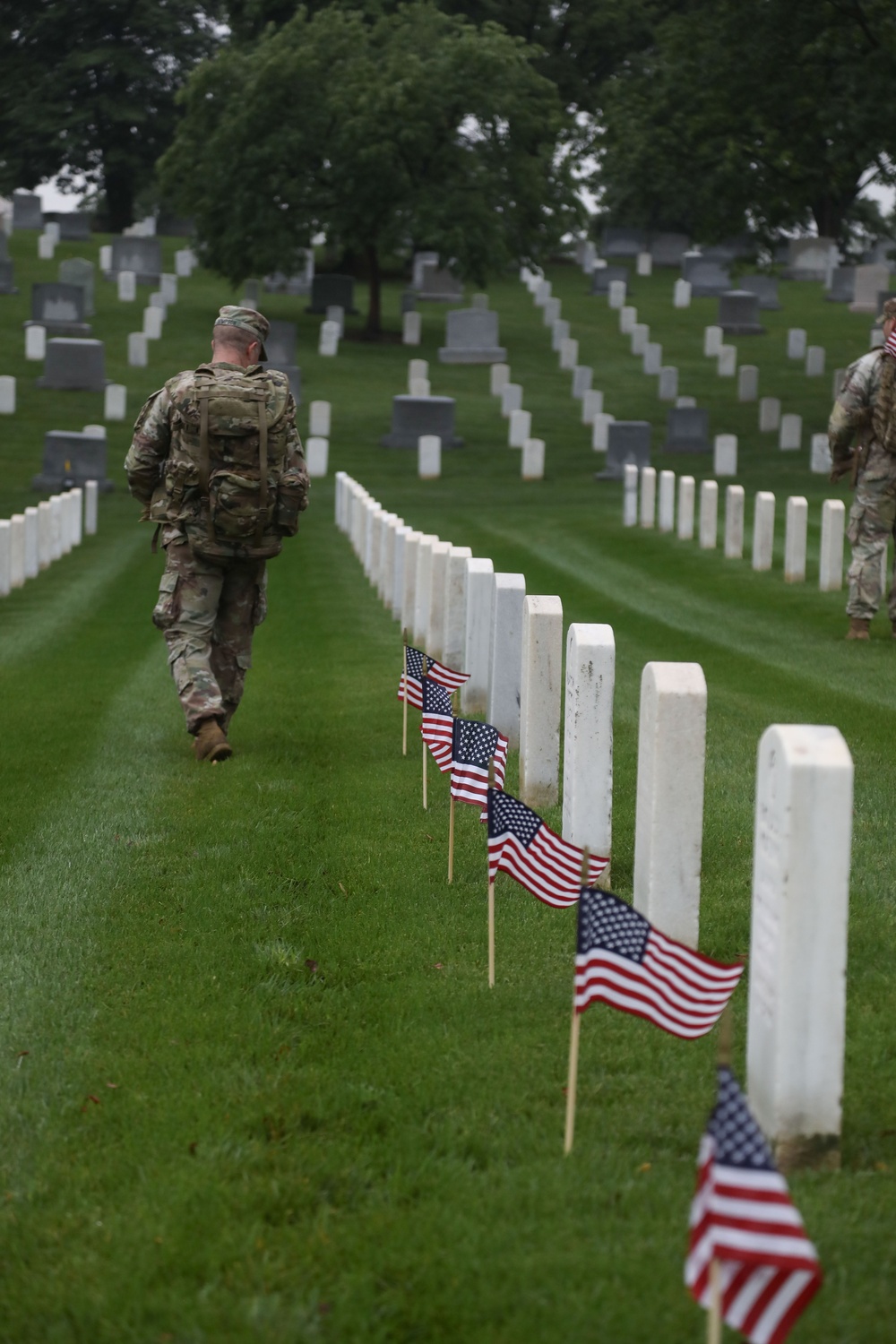 A Soldier from the 3d U.S. Infantry Regiment (The Old Guard) places American flags at headstones as part of &quot;Flags In&quot; at Arlington National Cemetery, Arlington, Va., May 22, 2025.