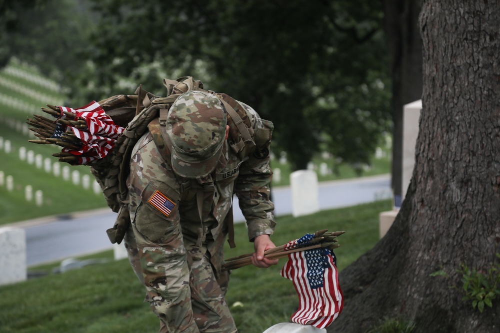 A Soldier from the 3d U.S. Infantry Regiment (The Old Guard) places American flags at headstones as part of &quot;Flags In&quot; at Arlington National Cemetery, Arlington, Va., May 22, 2025.