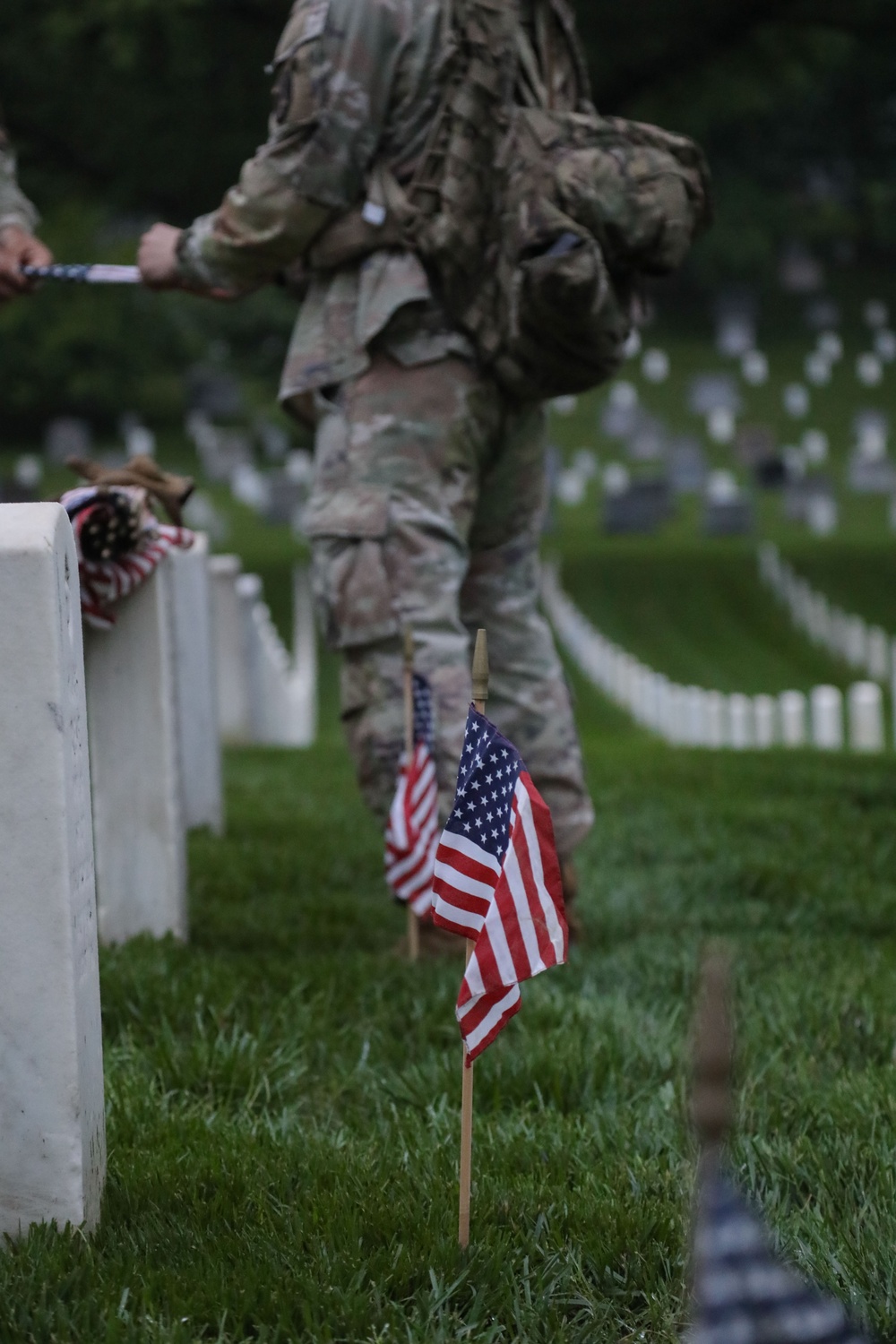 Soldiers from the 3d U.S. Infantry Regiment (The Old Guard) place American flags at headstones during “Flags In” at Arlington National Cemetery, Arlington, Va., May 22, 2025.
