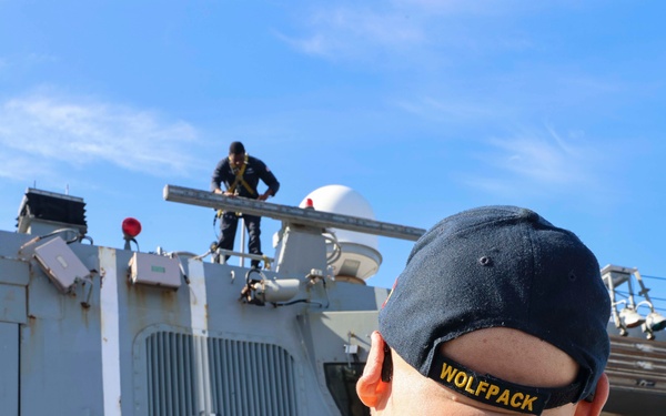 U.S. Navy Sailors prepare surfaces for preservation and painting while working aloft