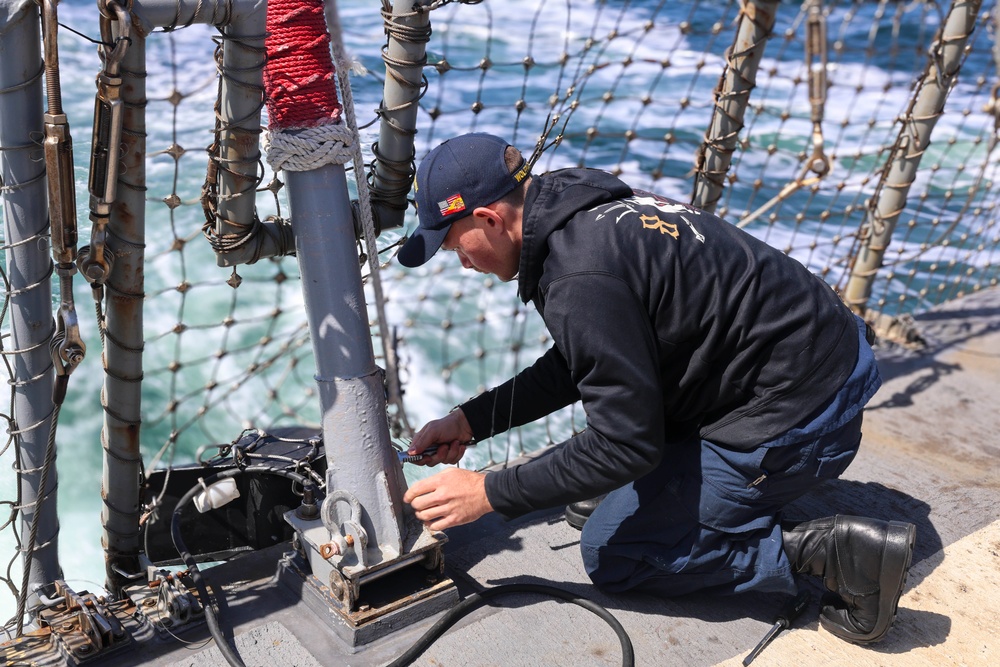 Fire Controlman 2nd Class Jalen Ross  installs the aft flag staff to the flight deck