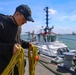 Boatswain’s Mate 3rd Class Johnathon Reynolds prepares to throw a mooring line to an approaching tug boat