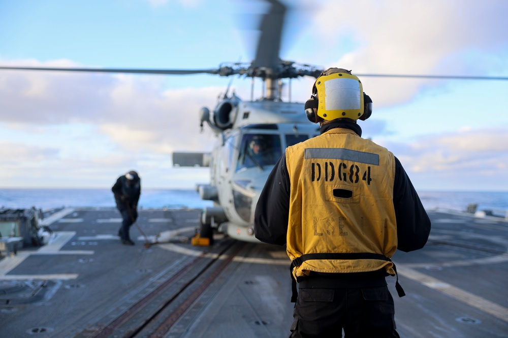BM1 Jason Carpenter signals to the MH-60R Sea Hawk helicopter pilot