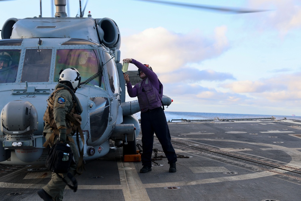 GSM2 Mark Bacca presents a fuel sample to the MH-60R Sea Hawk helicopter pilot