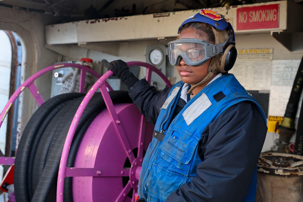 BM3 Sanaa Cooks unspools the re-fueling hose for a MH-60R Sea Hawk helicopter