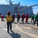 U.S. Navy Sailors conduct a foreign object debris walk-down to clean the flight deck