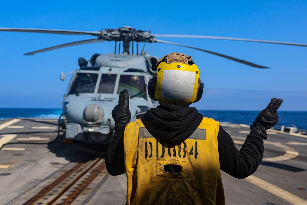 BM3 Sanaa Cooks signals to MH-60R Sea Hawk helicopter pilots
