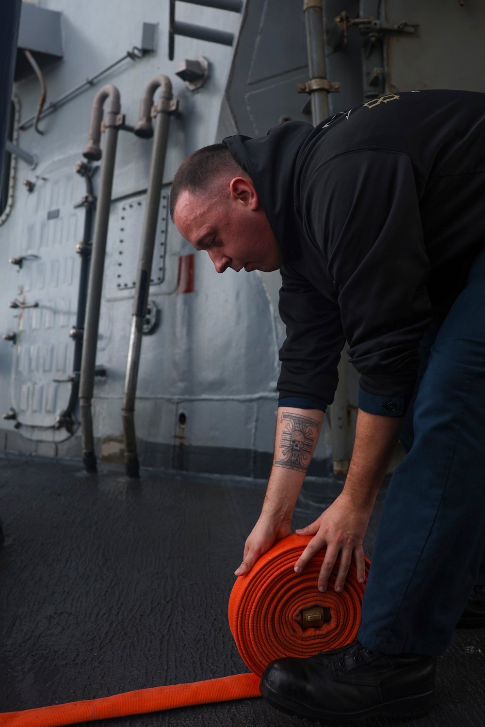 IT1 Michael Jordan stows a fire hose after conducting a fresh water wash down