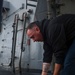 IT1 Michael Jordan stows a fire hose after conducting a fresh water wash down