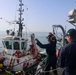 BM3 Sanaa Cooks throws a mooring ball and heaving line to an approaching tug boat