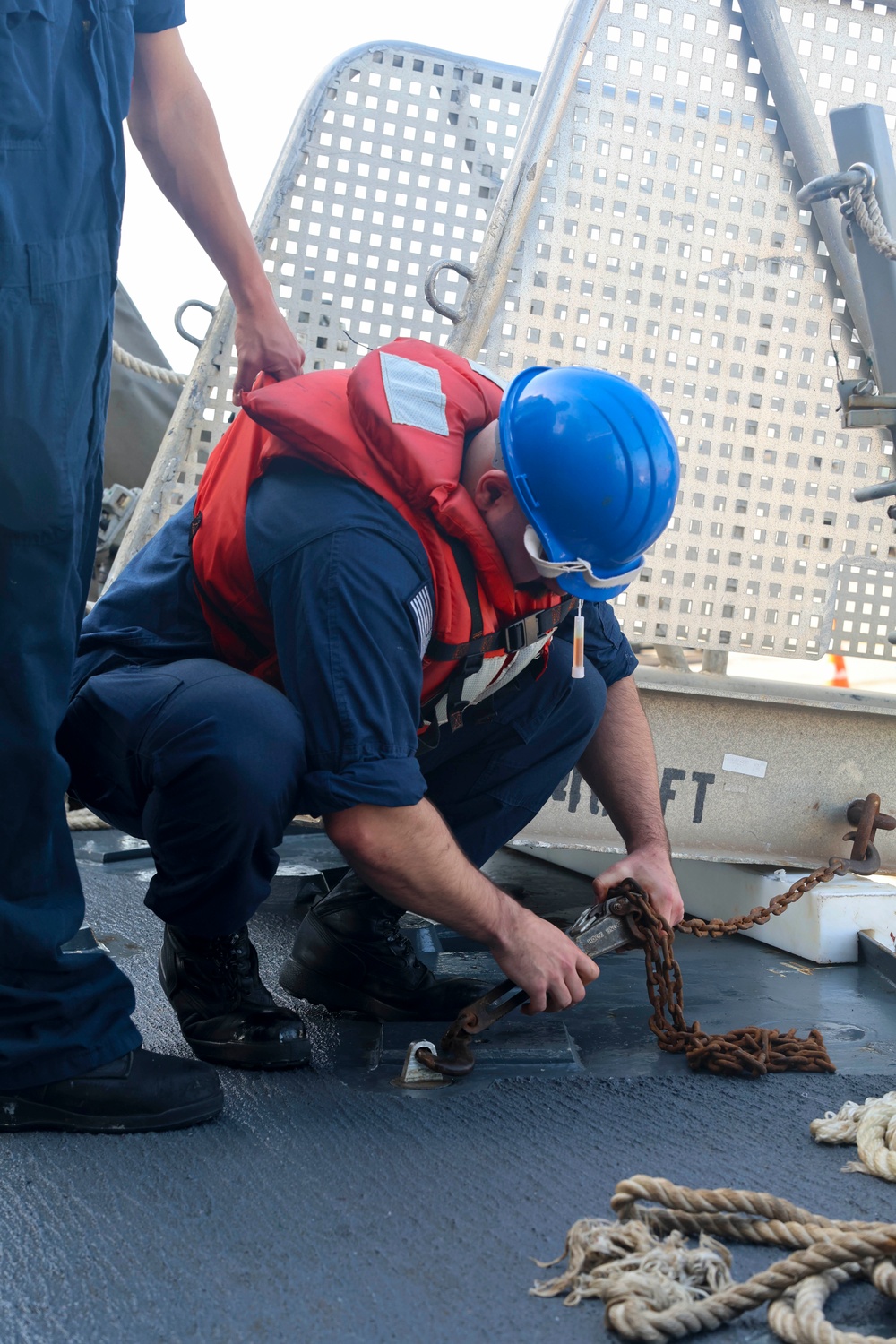 ET3 Joseph Keller attaches the brow to the deck with chain fasteners