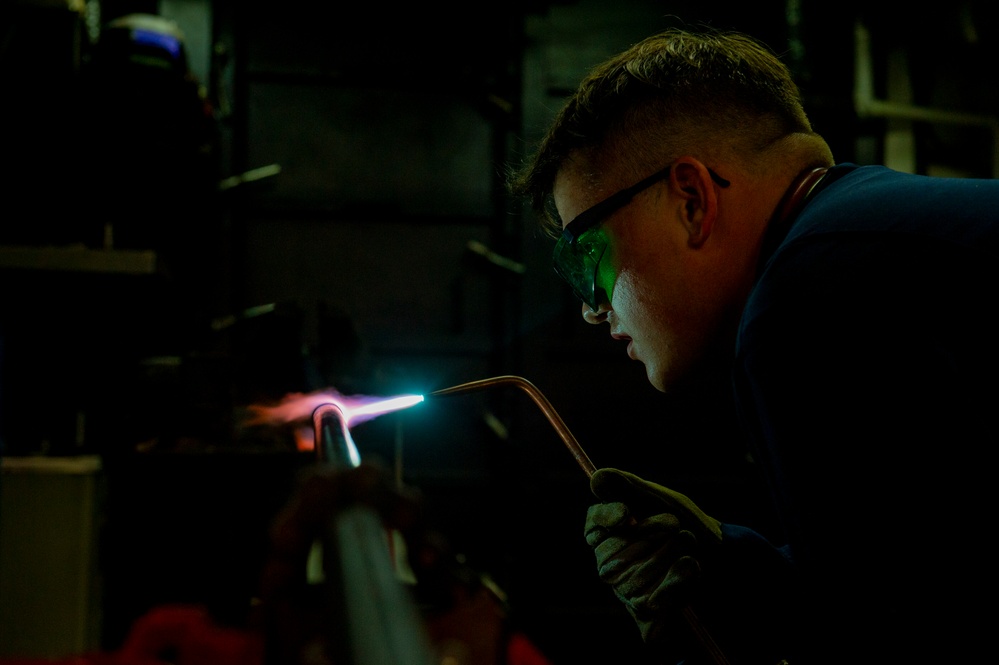 Hull Maintenance Technician anneals a carbon steel pipe while underway in the Pacific Ocean