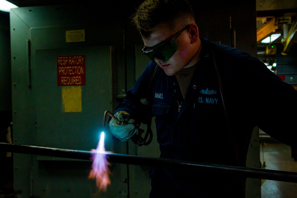 Hull Maintenance Technician anneals a carbon steel pipe while underway in the Pacific Ocean