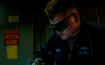 Hull Maintenance Technician anneals a carbon steel pipe while underway in the Pacific Ocean