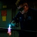 Hull Maintenance Technician anneals a carbon steel pipe while underway in the Pacific Ocean