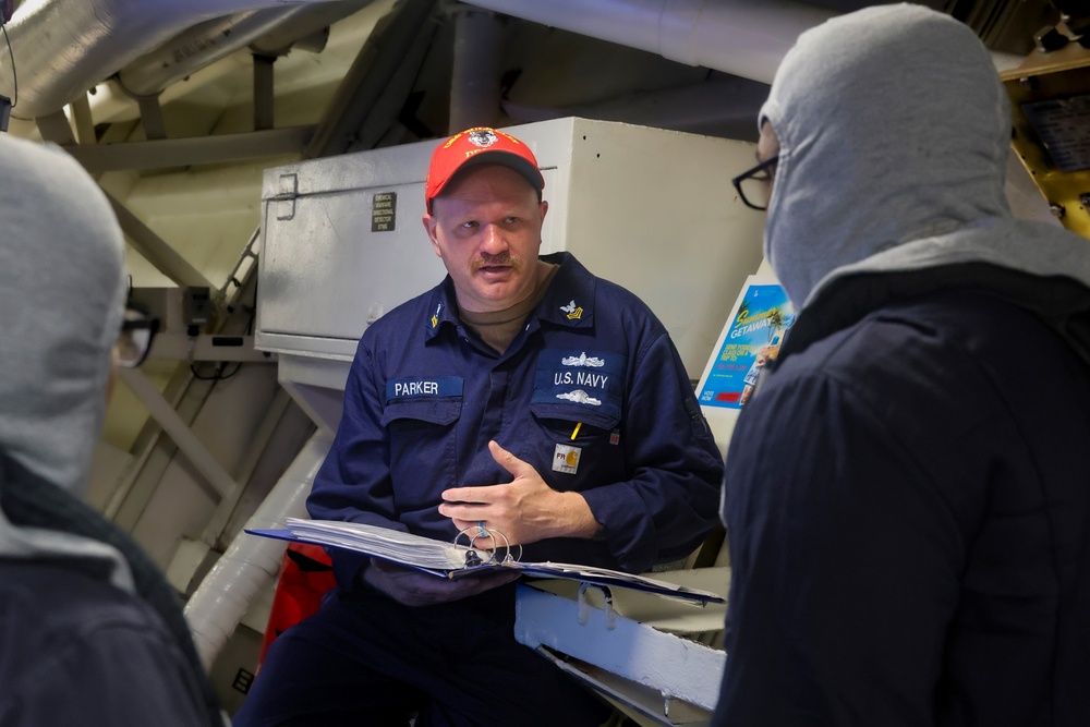 EM1 Kevin Parker conducts a damage control training debrief with crew members