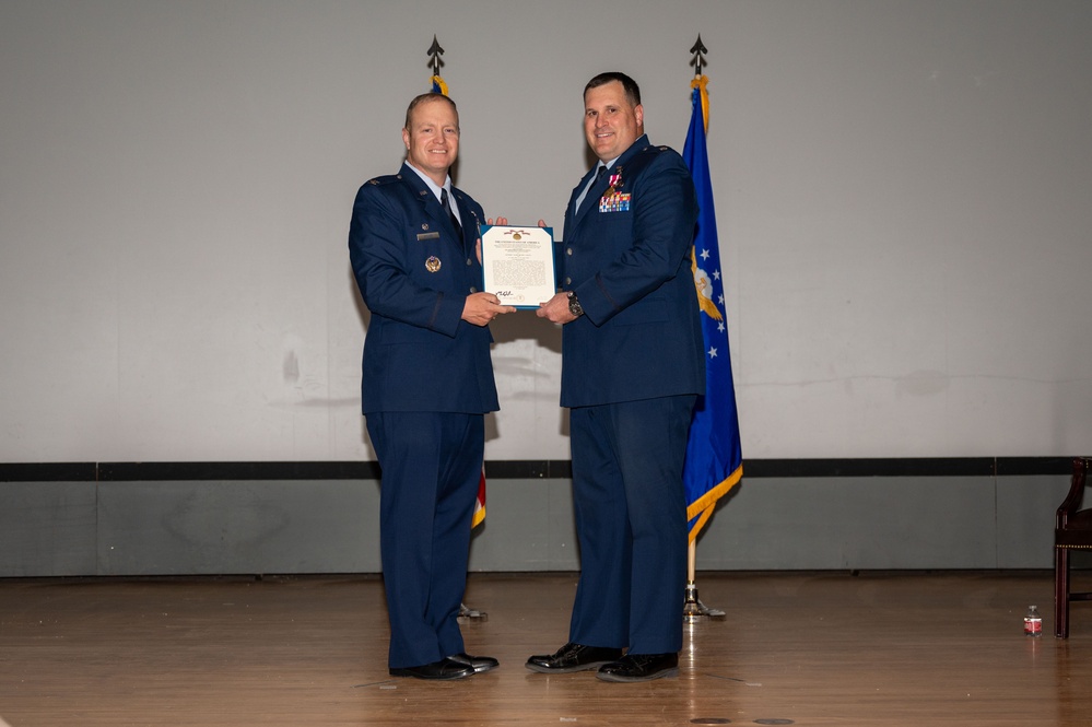 Col. Michael Power, 377th Air Base Wing and installation commander, presents a service award to Col. Matthew Daniels during the 377th Comptroller Squadron change of command ceremony