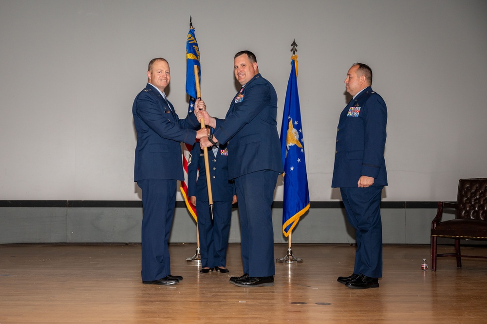 Lt. Col. Matthew Daniels, outgoing 377th Comptroller Squadron commander, passes the unit guidon to Col. Michael Power, 377th Air Base Wing and installation commander, during the 377th CPTS change of command ceremony