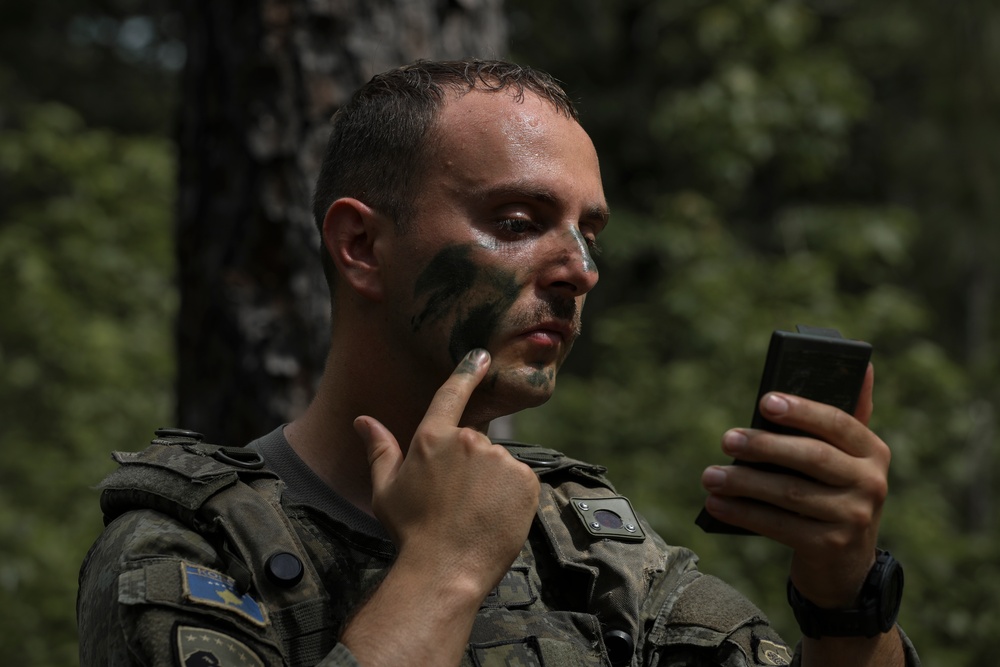 Kosovo Security Force soldier applies face paint during training at JRTC