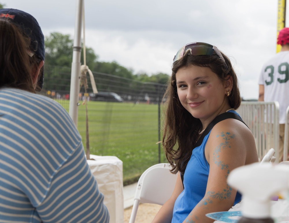 A young girl smiles while getting a temporary tattoo on her arm at the 250th U.S. Army Birthday Festival