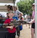 A little boy carefully handles a display weapon with his mother at the 250th U.S. Army Birthday Festival