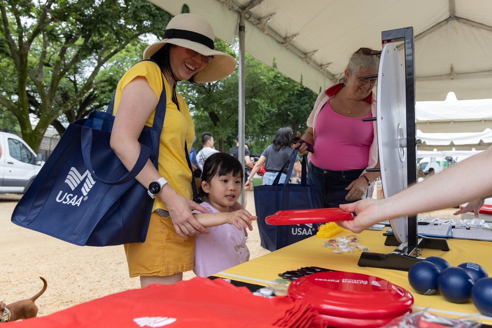 A little girl wins a free frisbee after spinning a prize wheel at the 250th U.S. Army Birthday Festival