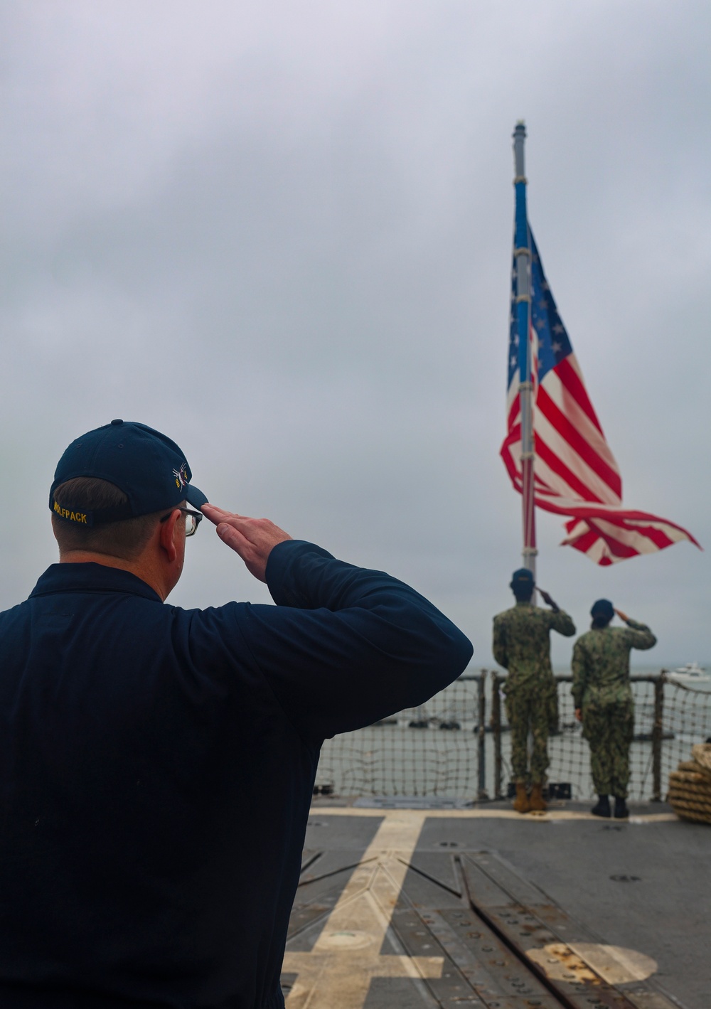 US Navy Sailors salute the ensign on the aft missile deck