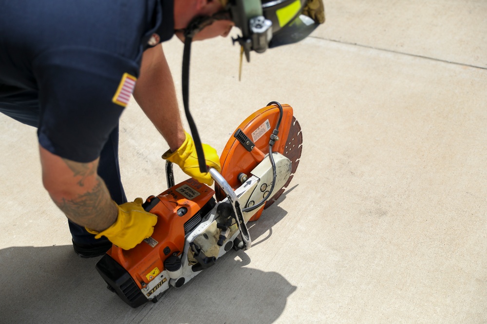 Firefighter Adam Burkholder cranks metal saw to improve mission readiness