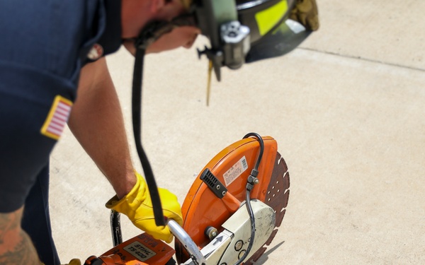 Firefighter Adam Burkholder cranks metal saw to improve mission readiness