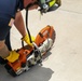 Firefighter Adam Burkholder cranks metal saw to improve mission readiness