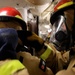 DC3 Luke Bryant assists another sailor with fitting firefighting gear