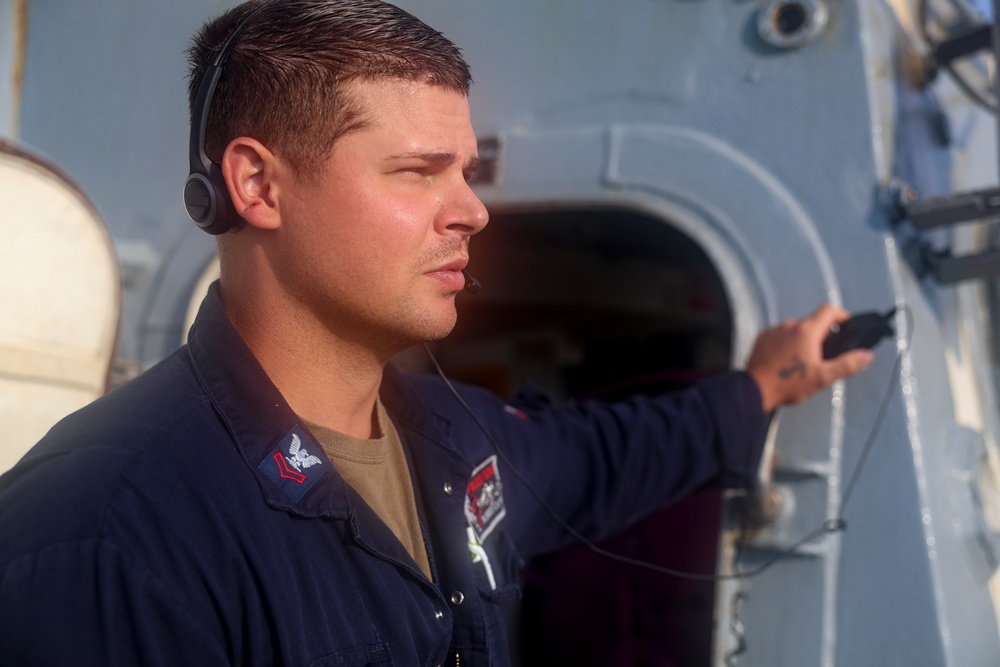 GSM2 Robert Capps operates a sound-powered telephone on the flight deck