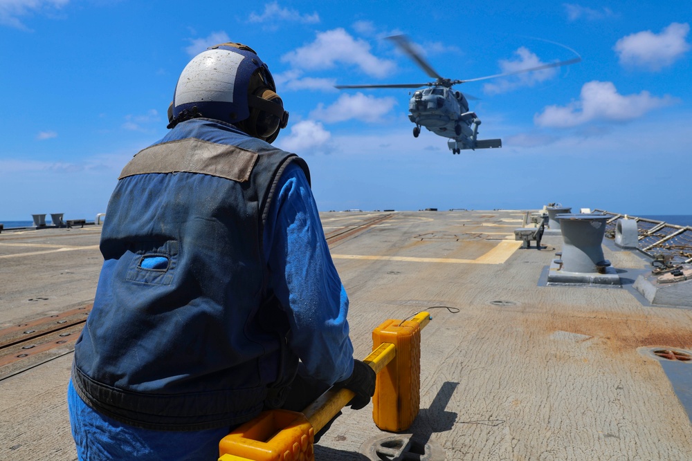 BM3 Sanaa Cooks waits with chocks and chains for a MH-60R Seahawk