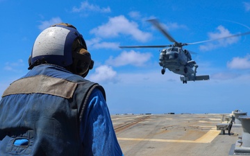 BM3 Sanaa Cooks waits with chocks and chains for a MH-60R Seahawk