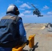 BM3 Sanaa Cooks waits with chocks and chains for a MH-60R Seahawk