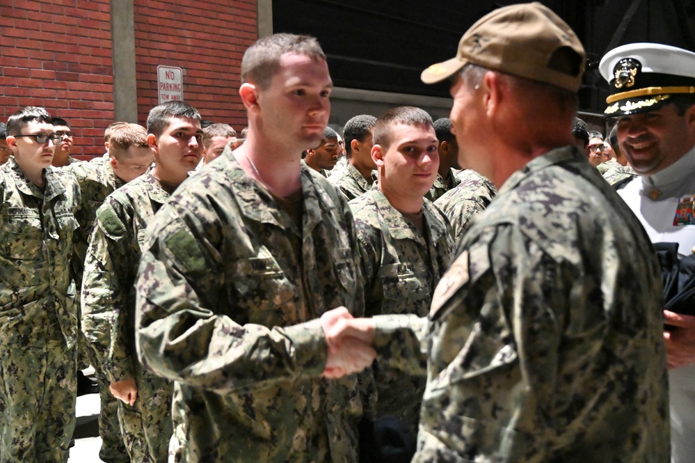 Captain Christopher May presents son with Navy ball cap after Battle Stations evolution at Recruit Training Command.