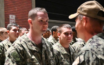Captain Christopher May presents son with Navy ball cap after Battle Stations evolution at Recruit Training Command.